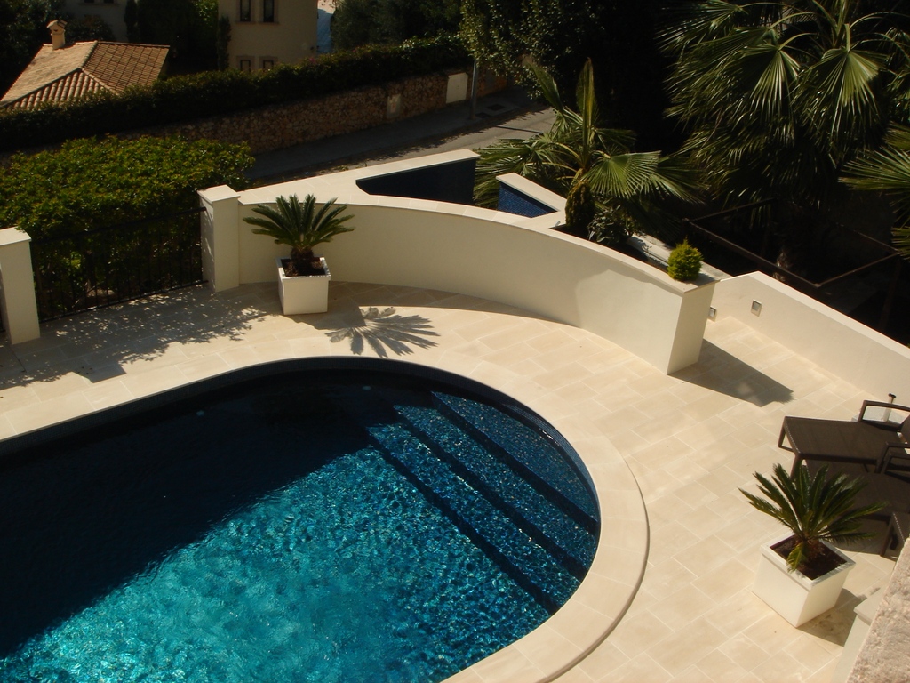 Geschwungener Pool mit Travertin-Terrasse